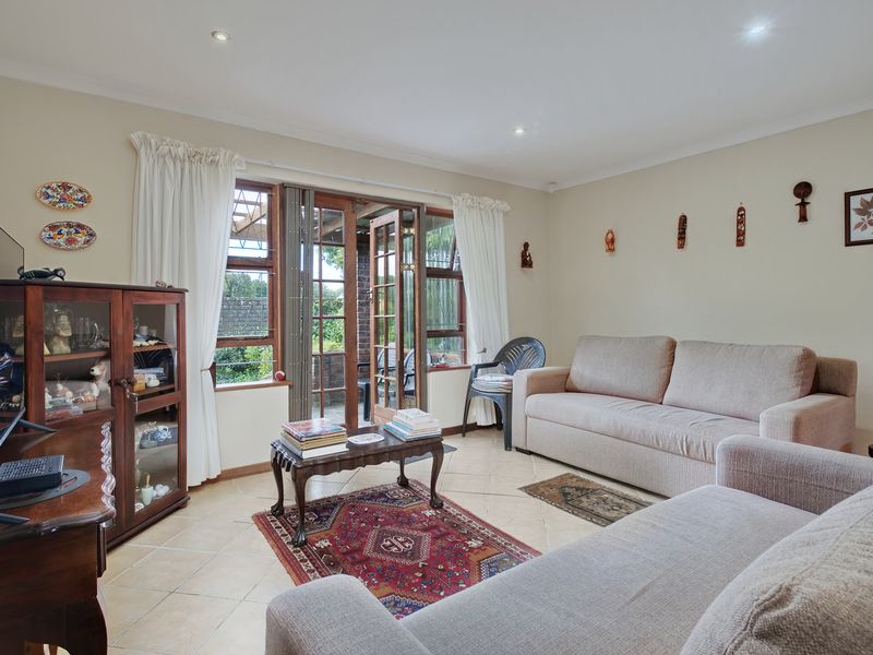A comfortable living room featuring tiled flooring, recessed lighting, and wooden framed glass doors providing direct access to the outdoor patio area.