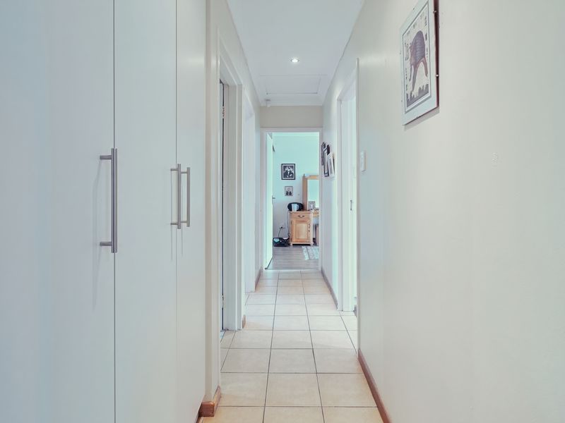 A bright hallway featuring tiled flooring and extensive built-in cupboard storage, providing a clean and functional transition between rooms.