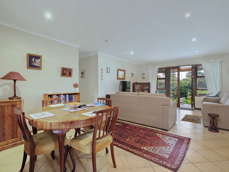 Open plan living and dining area featuring tiled flooring, recessed lighting, and direct access to the rear garden through glass french doors.