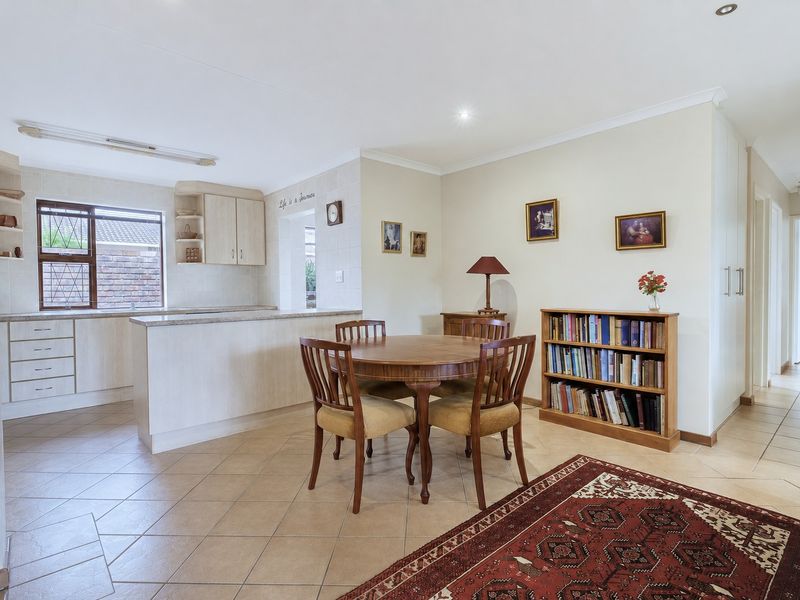 Open-plan kitchen and dining area featuring tiled flooring, neutral cabinetry, and a breakfast counter, providing a functional and connected living space.