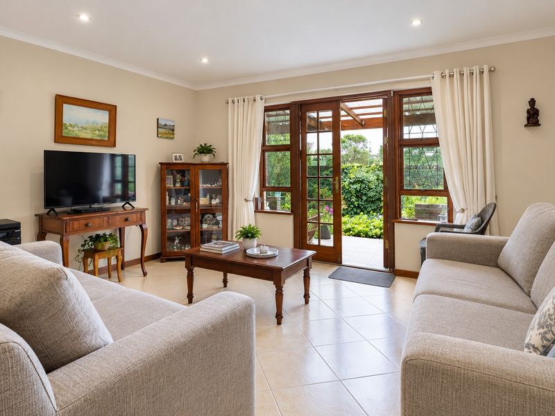 A bright living room featuring tiled flooring, recessed lighting, and timber-framed glass doors providing direct access to the outdoor patio area.