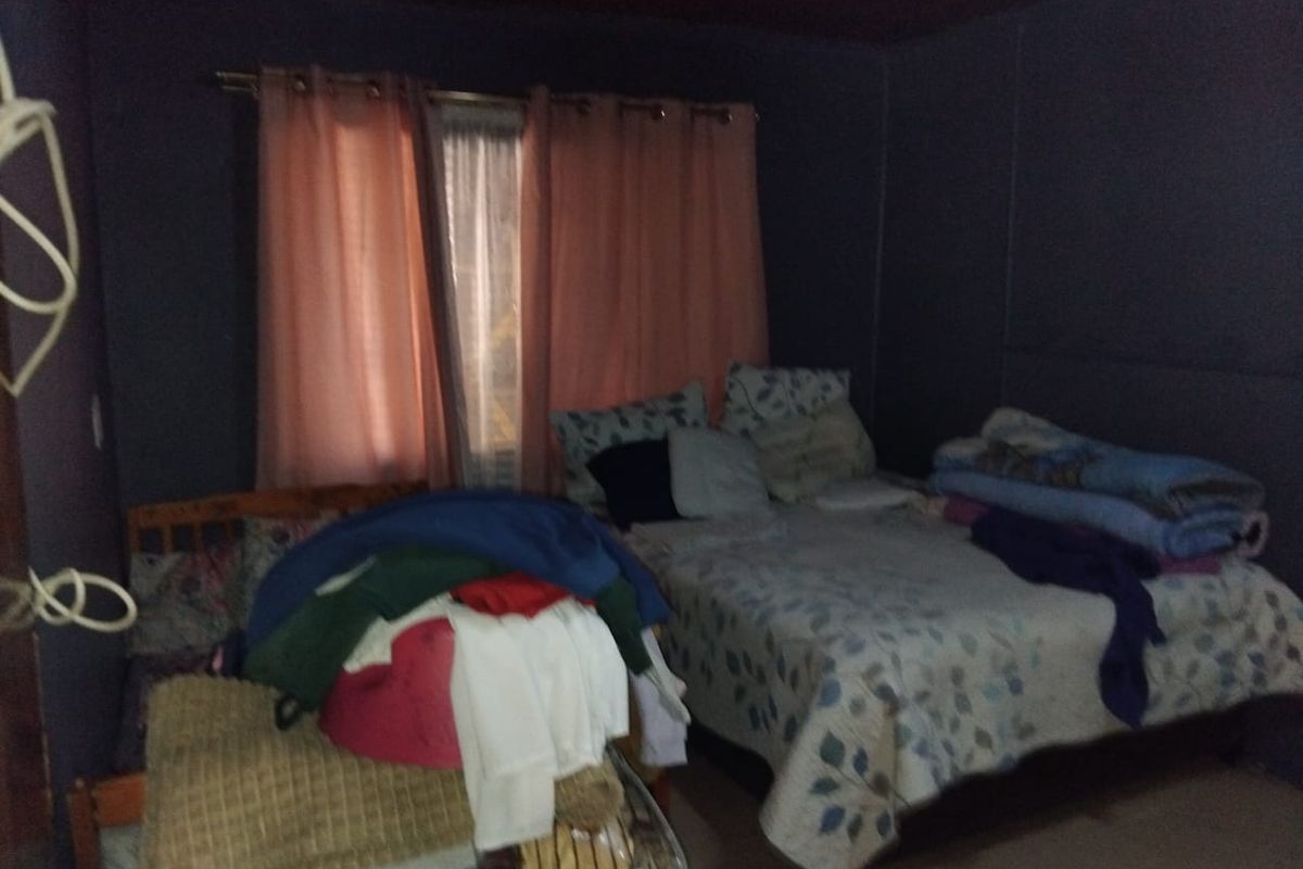 A bedroom featuring dark walls and a timber ceiling, requiring updates to improve lighting and overall finish.