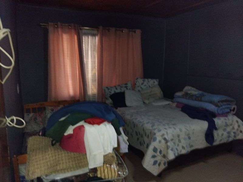 A bedroom featuring dark walls and a timber ceiling, requiring updates to improve lighting and overall finish.