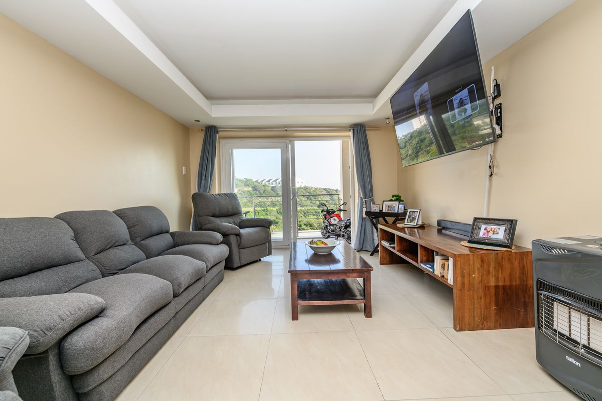 A bright living room featuring tiled flooring, a recessed ceiling, and a sliding glass door providing access to an outdoor balcony area.