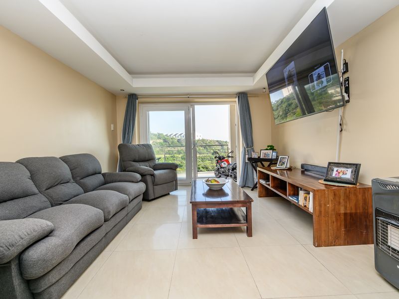 A bright living room featuring tiled flooring, a recessed ceiling, and a sliding glass door providing access to an outdoor balcony area.
