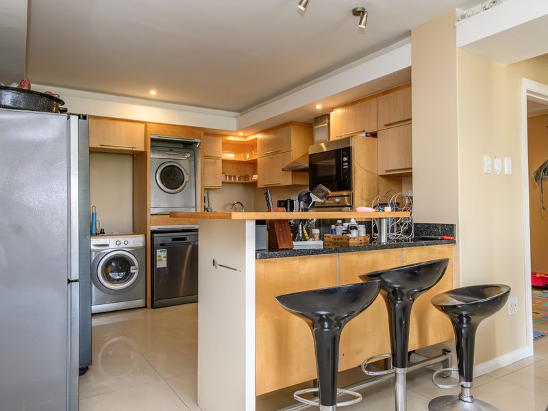 A functional kitchen featuring light wood cabinetry, granite countertops, a breakfast bar, and integrated appliances including an oven and extractor fan.