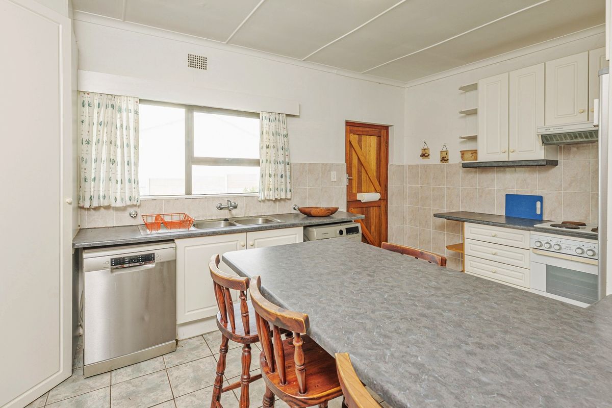 A functional kitchen featuring white cabinetry, laminate countertops, a double basin sink, and built-in cooking appliances with tiled flooring and splashbacks.