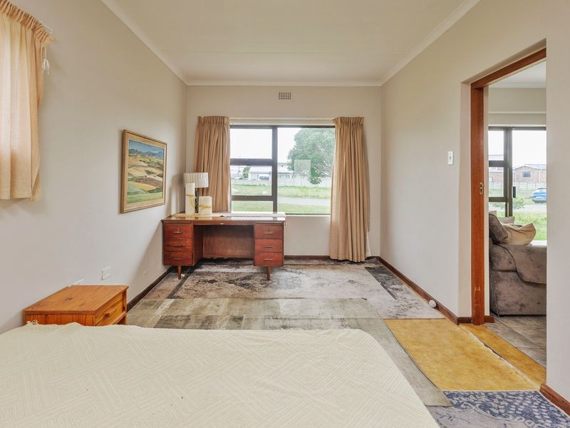 A bedroom featuring aluminium window frames and coved ceilings, currently requiring flooring updates and general cosmetic refurbishment to improve its overall appeal.