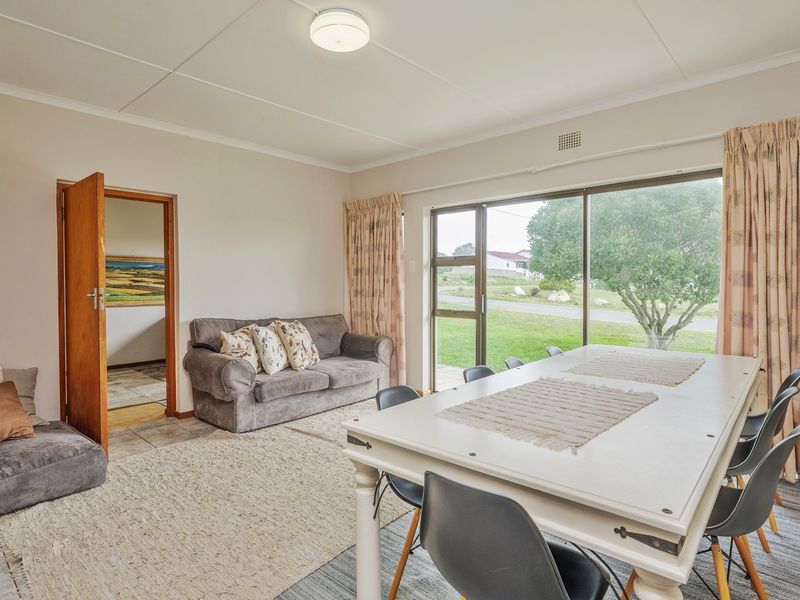 An open-plan living and dining area featuring tiled flooring, a large sliding glass door providing natural light, and direct access to an adjacent room.