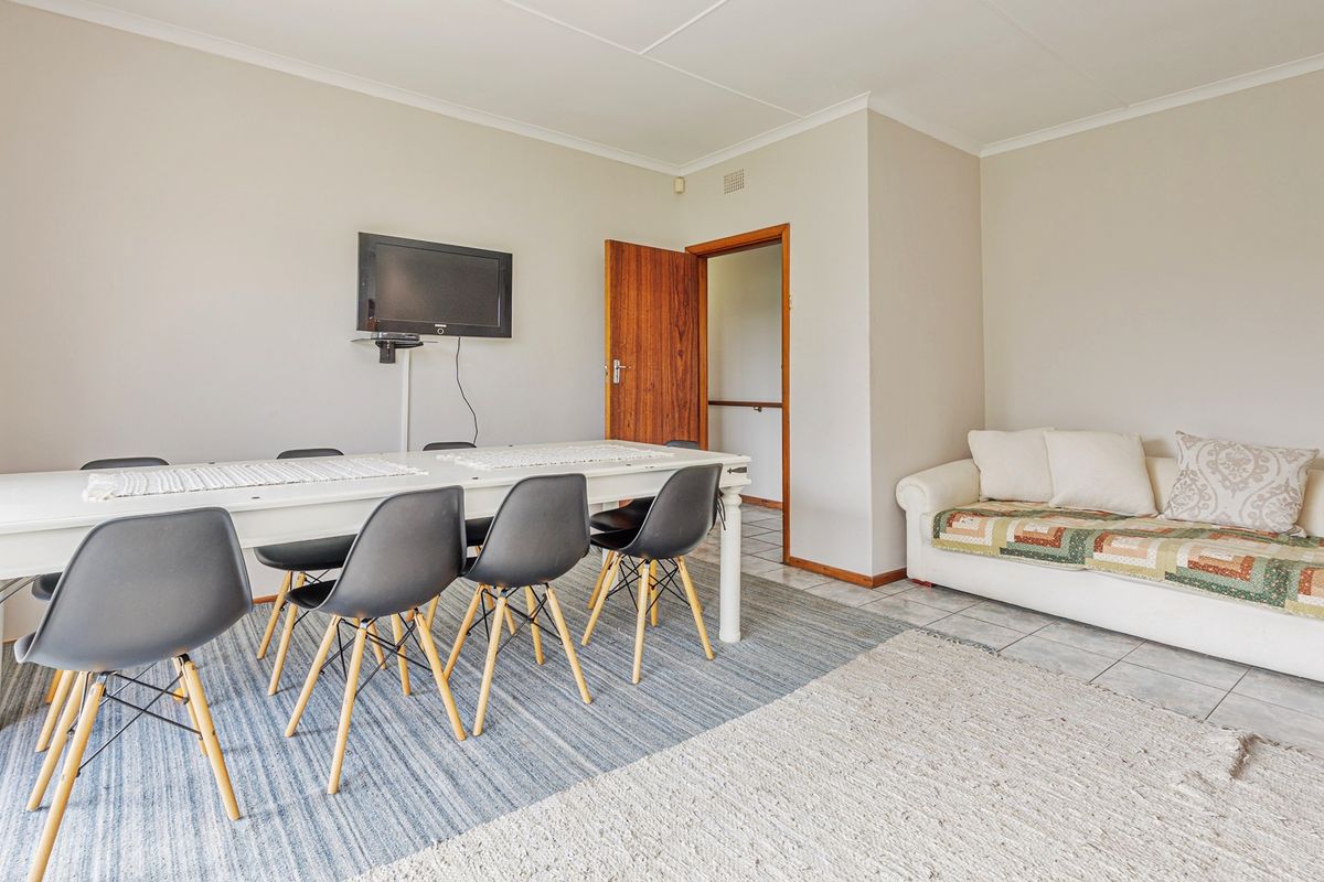 A functional living and dining area featuring tiled flooring, neutral walls, and a timber door leading to an adjacent space.