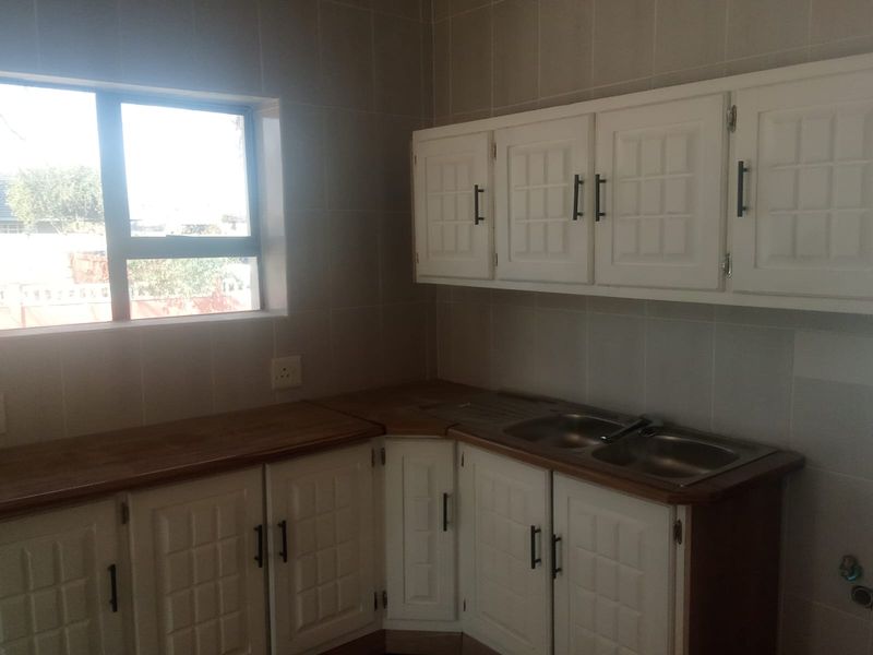 A functional kitchen area featuring white built-in cabinetry, a double bowl sink, and wooden countertops with tiled wall finishes.