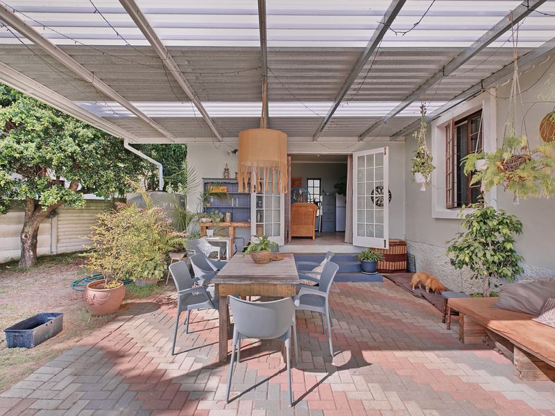 Covered outdoor patio area featuring brick paving, a corrugated roof structure, and direct access to the interior through double french doors.