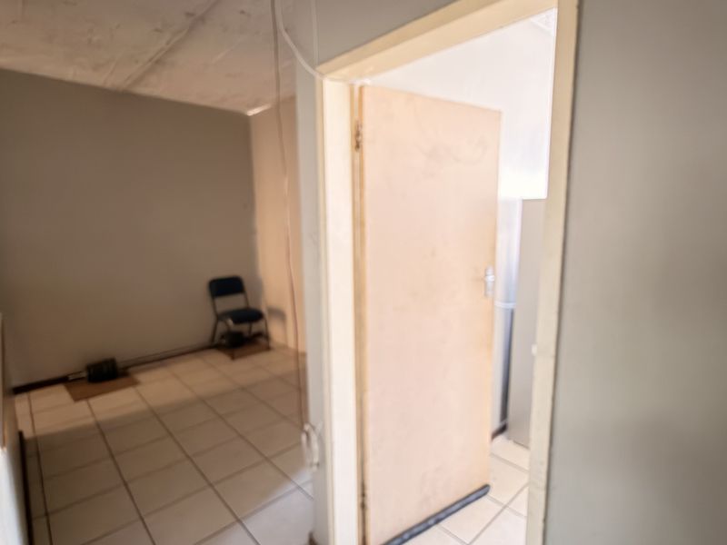 A simple hallway area featuring tiled flooring and a wooden internal door, providing access between rooms in the flat.
