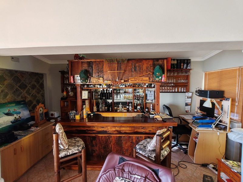 A dedicated home bar area featuring custom built-in wooden cabinetry, a solid wood bar counter, and tiled flooring.