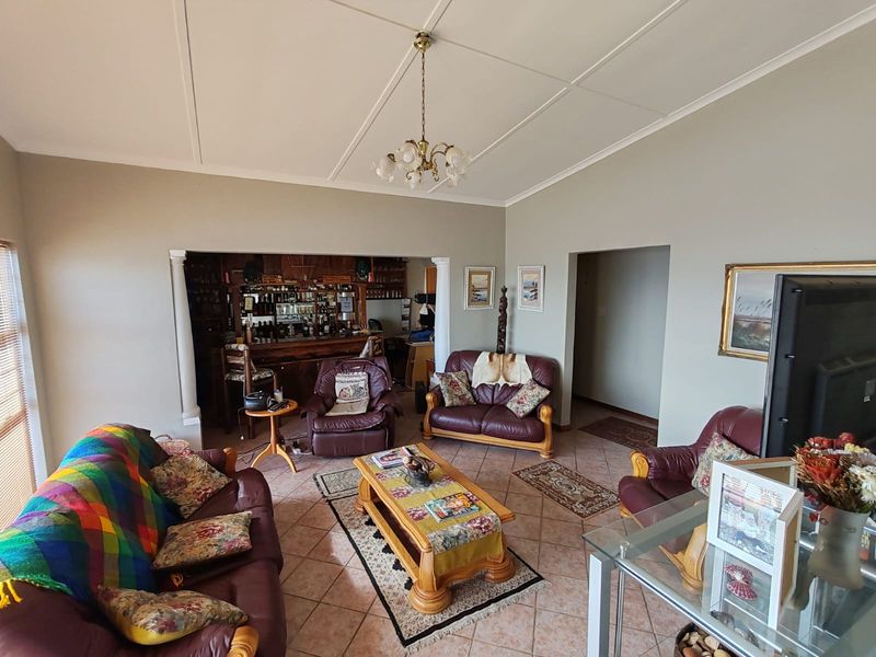 Spacious living room featuring tiled flooring, coved cornicing, and a built-in bar area, offering a comfortable and functional layout.