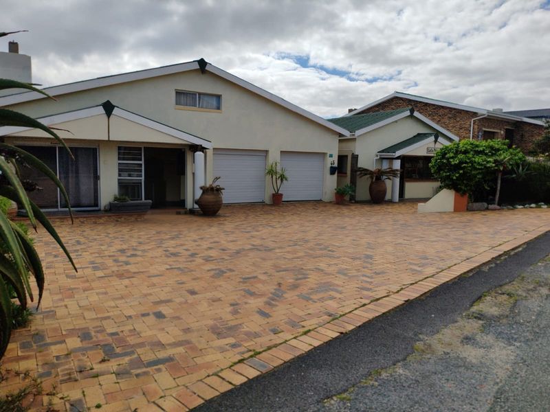 Front elevation of a residential property featuring a paved driveway, double garage, and gabled roof architecture.