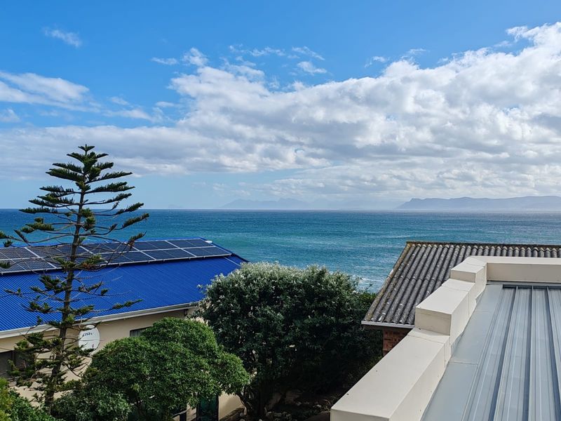 Elevated coastal view overlooking the ocean with visible solar panels on the adjacent roof structure.