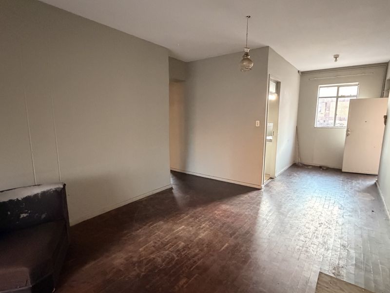An empty living area featuring original parquet flooring and neutral walls, offering a blank canvas for renovation and interior design updates.