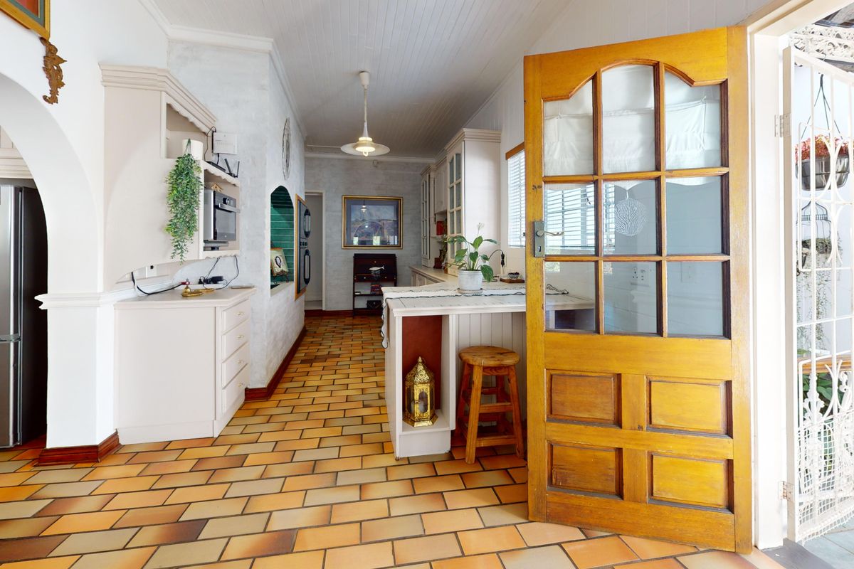 A rustic kitchen featuring terracotta-style tiled flooring, built-in cabinetry, and a classic timber door leading to an outdoor area.