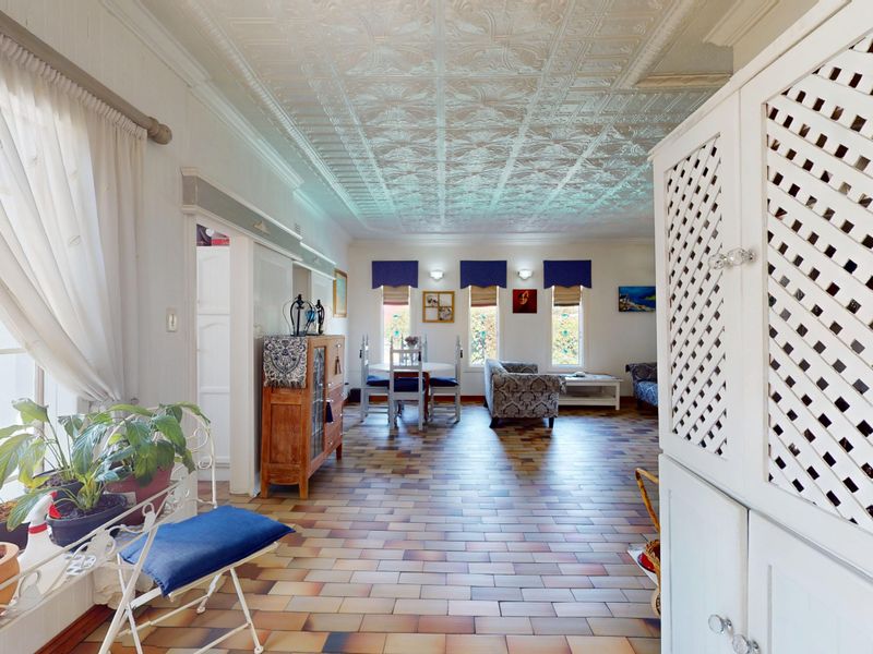 Spacious open-plan living and dining area featuring unique pressed metal ceilings and traditional terracotta tile flooring with abundant natural light.