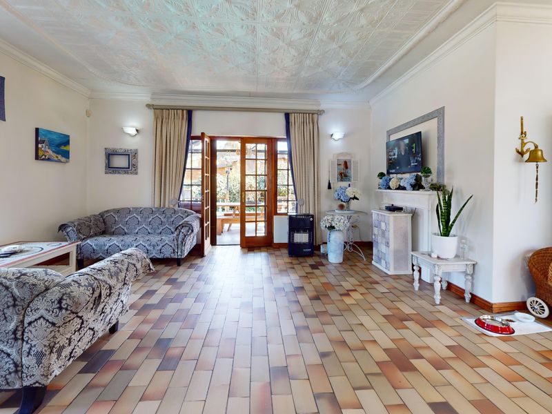 Spacious living room featuring a decorative pressed metal ceiling, tiled flooring, and direct access to the outdoor patio through classic French doors.