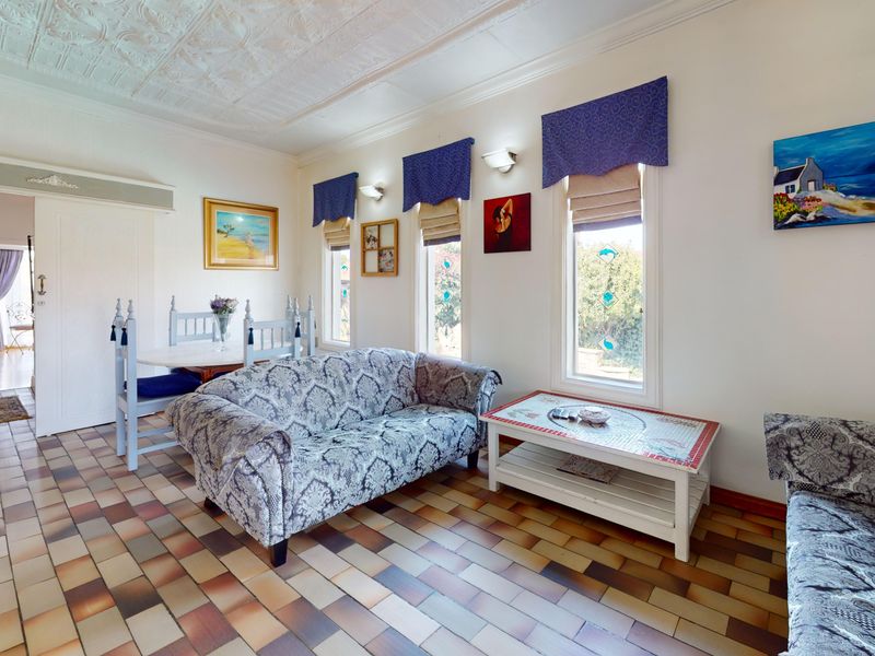 A living room featuring traditional tiled flooring, a decorative pressed metal ceiling, and windows with stained glass accents.
