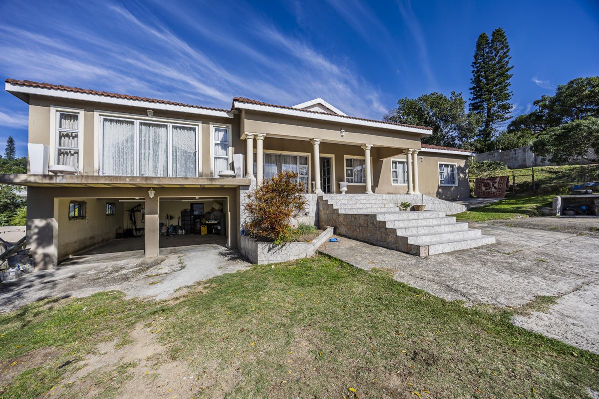 Rear view of the property featuring a tiled staircase leading to a patio, integrated garage space, and a concrete driveway area.