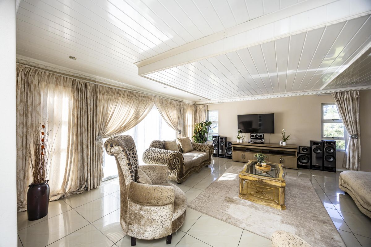 Spacious living room featuring tiled flooring, a distinctive tongue and groove ceiling, and large sliding glass doors that provide ample natural light.
