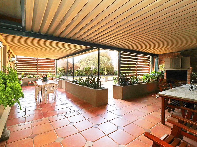 Spacious covered patio featuring tiled flooring, built-in brick fireplace, and integrated planters, providing an ideal area for outdoor entertaining.