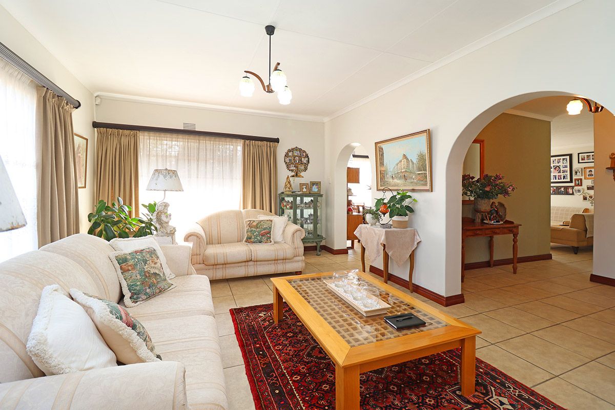 A spacious living room featuring tiled flooring, coved ceilings, and an open-plan archway leading to an adjacent area.