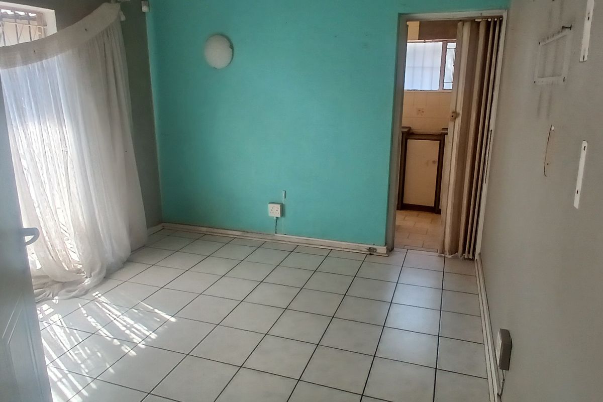 An empty bedroom featuring tiled flooring, a bright accent wall, and a folding door leading to an adjacent space.