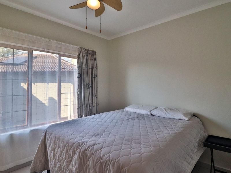 A functional bedroom featuring a ceiling fan and a large window that provides natural light.