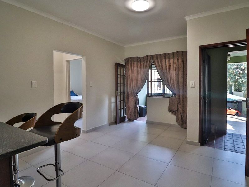 Open plan living area featuring neutral tiled flooring, direct access to an outdoor patio, and a seamless flow into adjacent rooms.