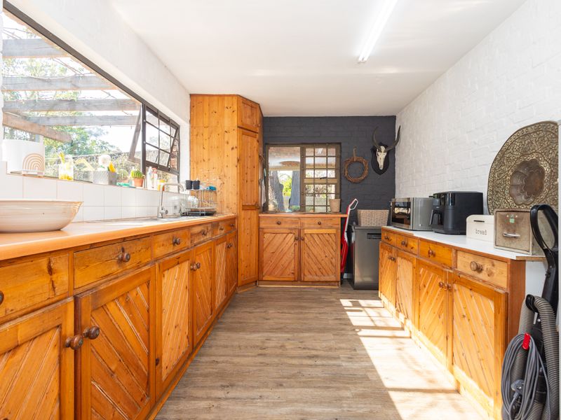 A functional kitchen featuring extensive wooden cabinetry, laminate countertops, and a tiled backsplash, offering a classic aesthetic with potential for modern updates.