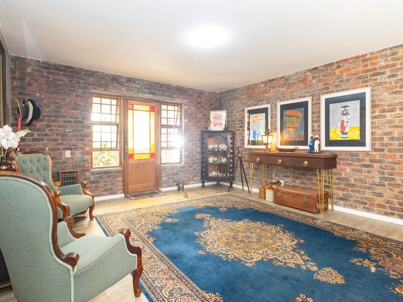 A welcoming entrance hall featuring characterful exposed brick walls, timber-framed front door with stained glass detailing, and durable laminate flooring.