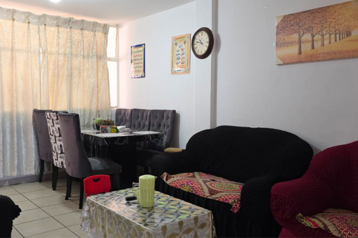 An open-plan living and dining area featuring tiled flooring and a large window with curtains, providing a functional and versatile space.