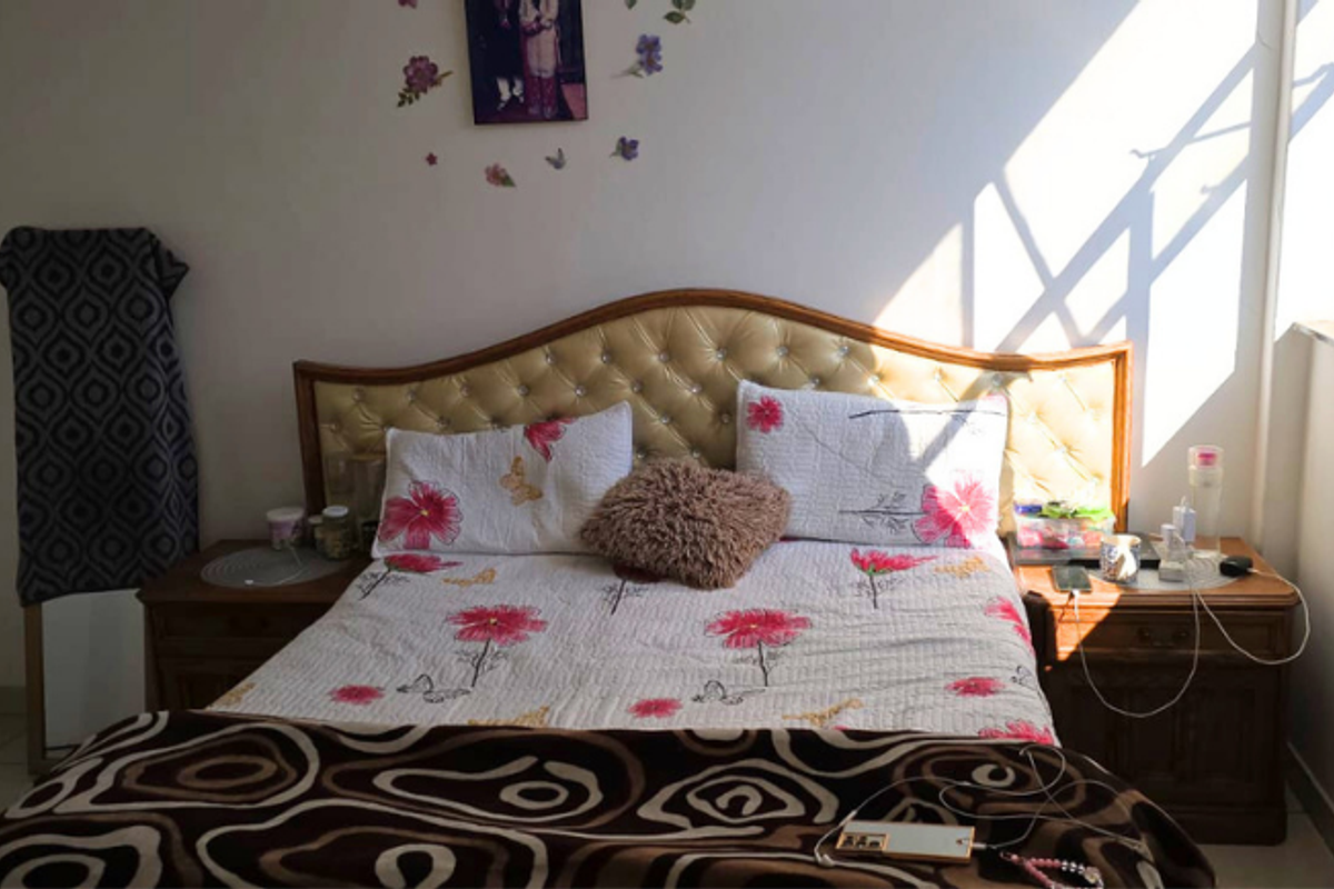 A functional bedroom featuring tiled flooring and a built-in wardrobe, benefiting from natural light through the side window.