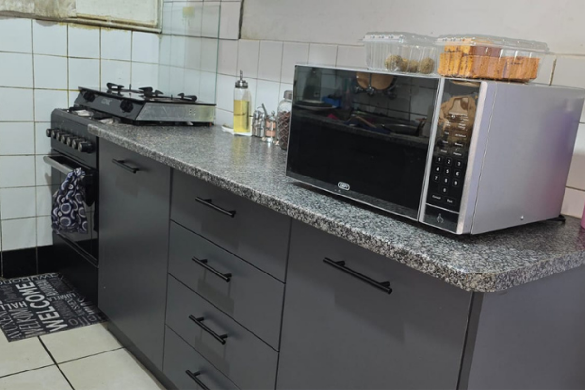 A functional kitchen area featuring modern grey cabinetry, granite countertops, a gas stove, and a tiled backsplash.