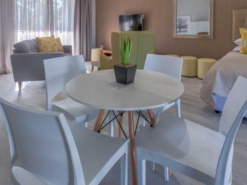 A well-maintained bedroom featuring light laminate flooring, neutral wall paneling, and floor-to-ceiling curtains providing ample natural light.