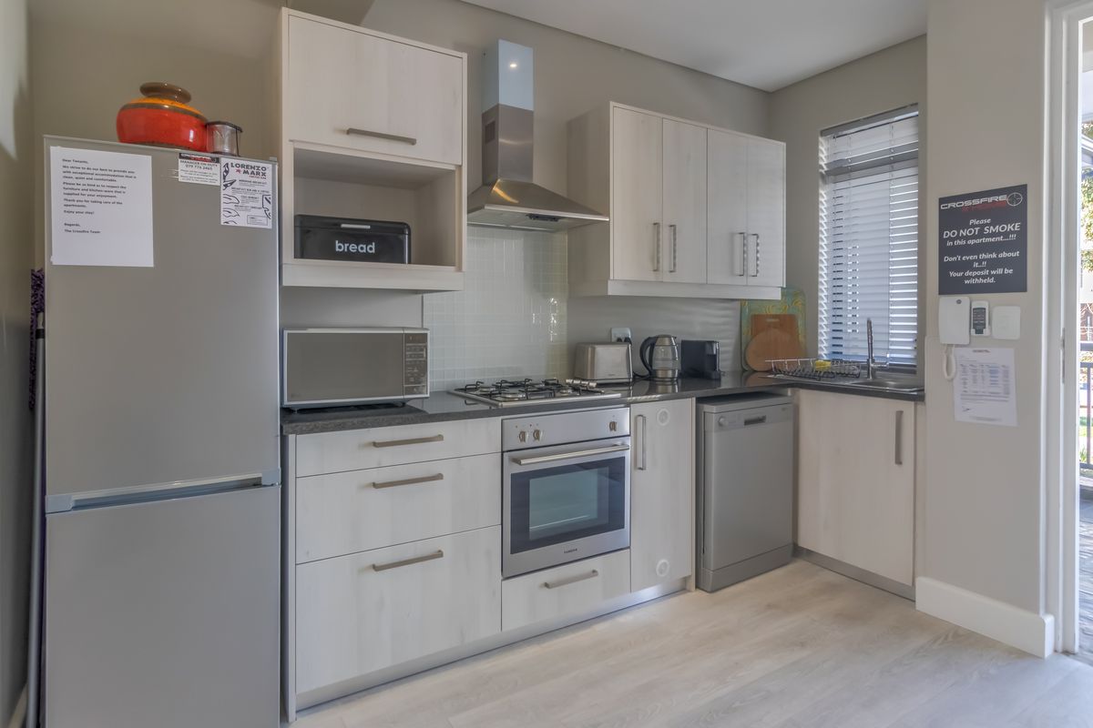 A modern, well-maintained kitchen featuring light wood-finish cabinetry, a gas hob, built-in oven, and integrated stainless steel sink with natural light.