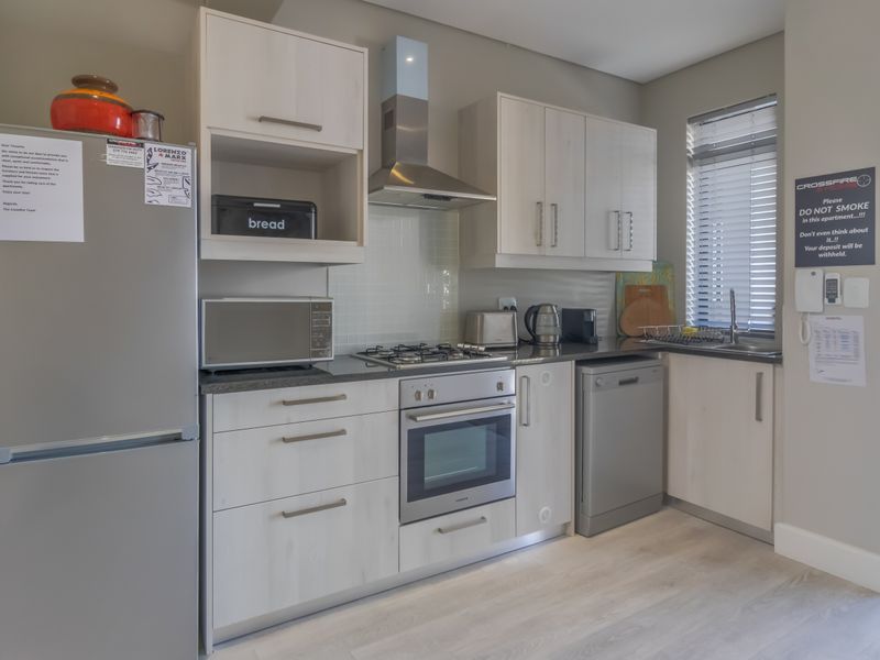 A modern, well-maintained kitchen featuring light wood-finish cabinetry, a gas hob, built-in oven, and integrated stainless steel sink with natural light.