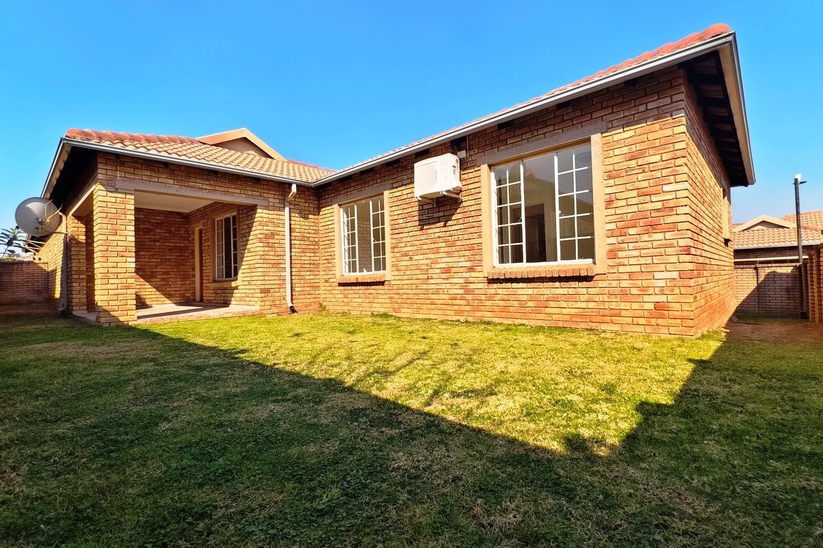 Rear view of the townhouse featuring a face brick exterior, a covered patio area, and a private garden space.
