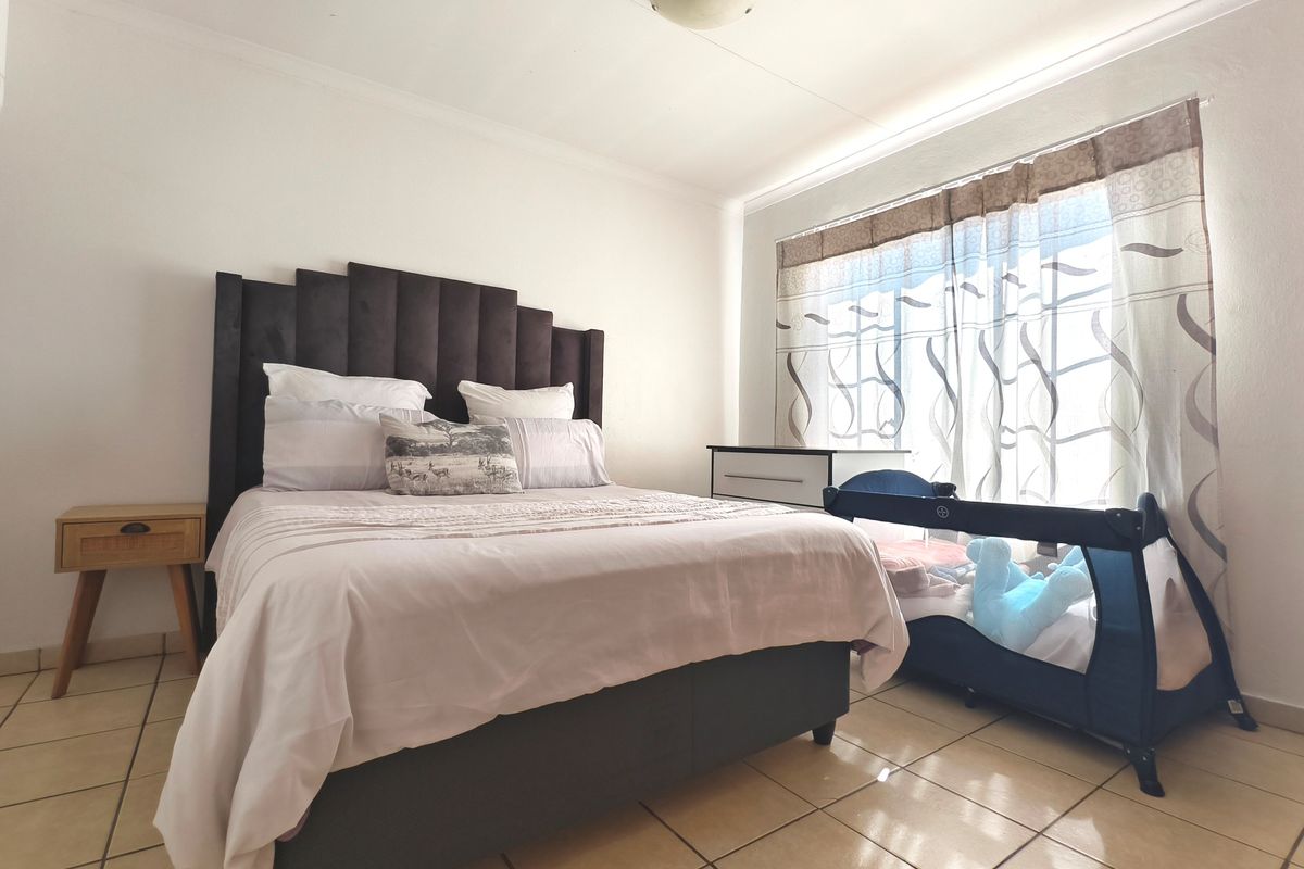 A well-lit bedroom featuring neutral tiled flooring and a standard ceiling light fixture, providing a functional and comfortable living space.