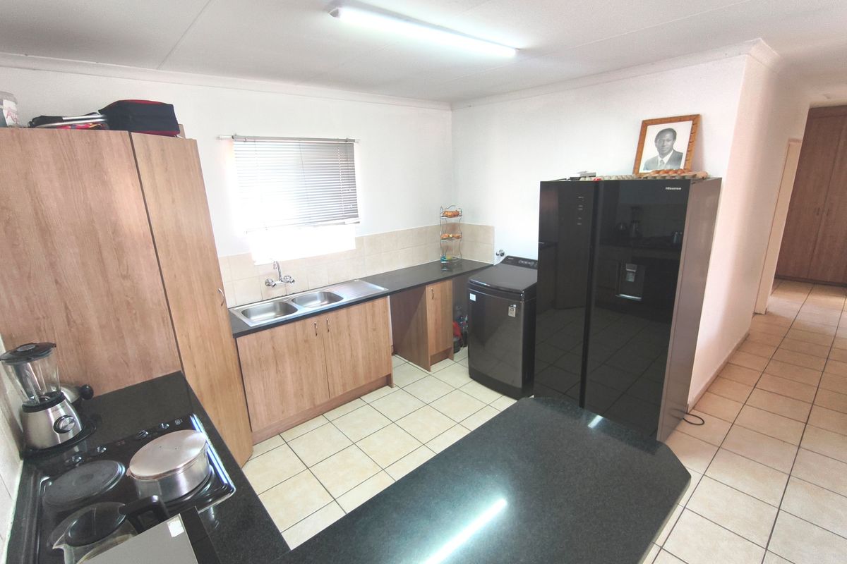 A functional kitchen featuring wood-finish cabinetry, granite countertops, a double sink, and ceramic tile flooring, providing a practical workspace.