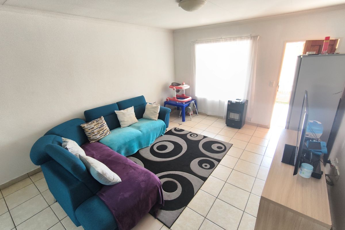 A living room area featuring tiled flooring and natural light from a window, providing a functional space for relaxation.