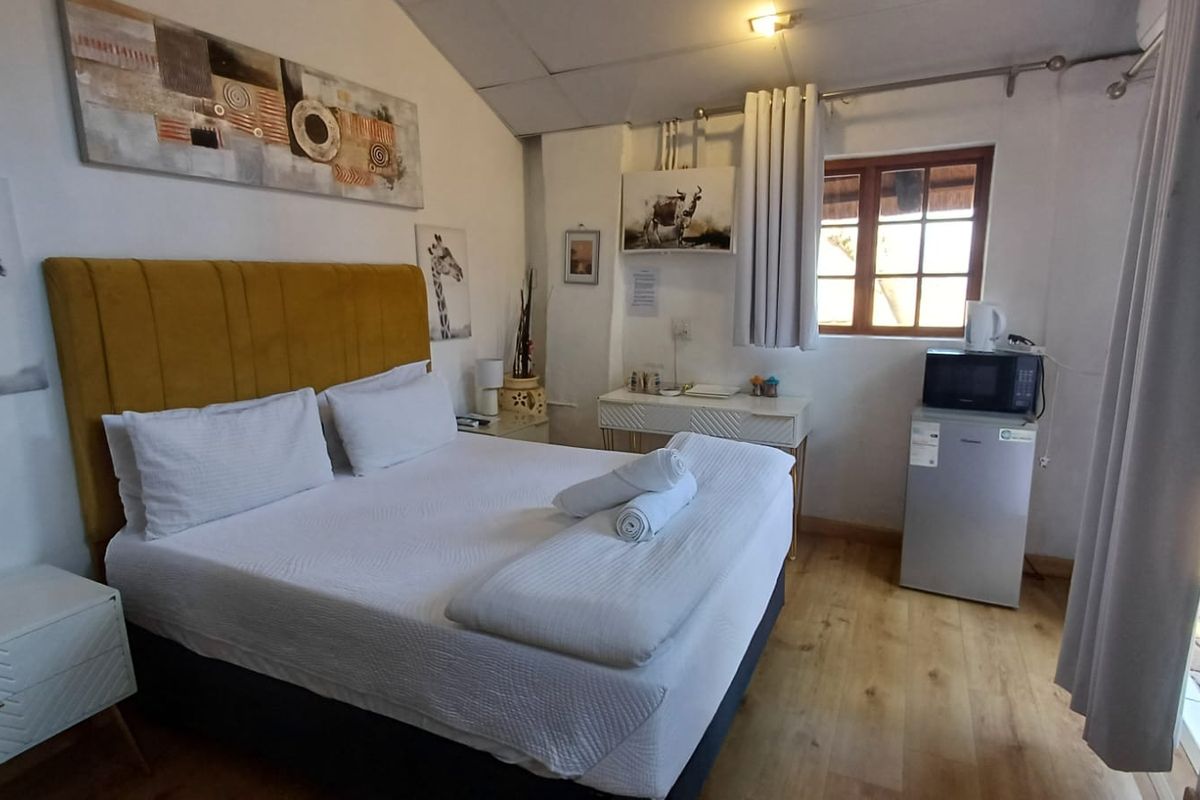 A compact bedroom featuring timber flooring, a timber-framed window, and a vaulted ceiling, providing a functional and cozy living space.