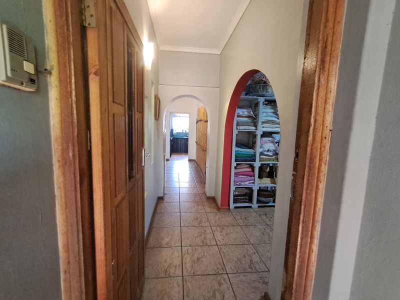 A tiled hallway featuring arched architectural details and an intercom system, providing access to adjacent rooms.