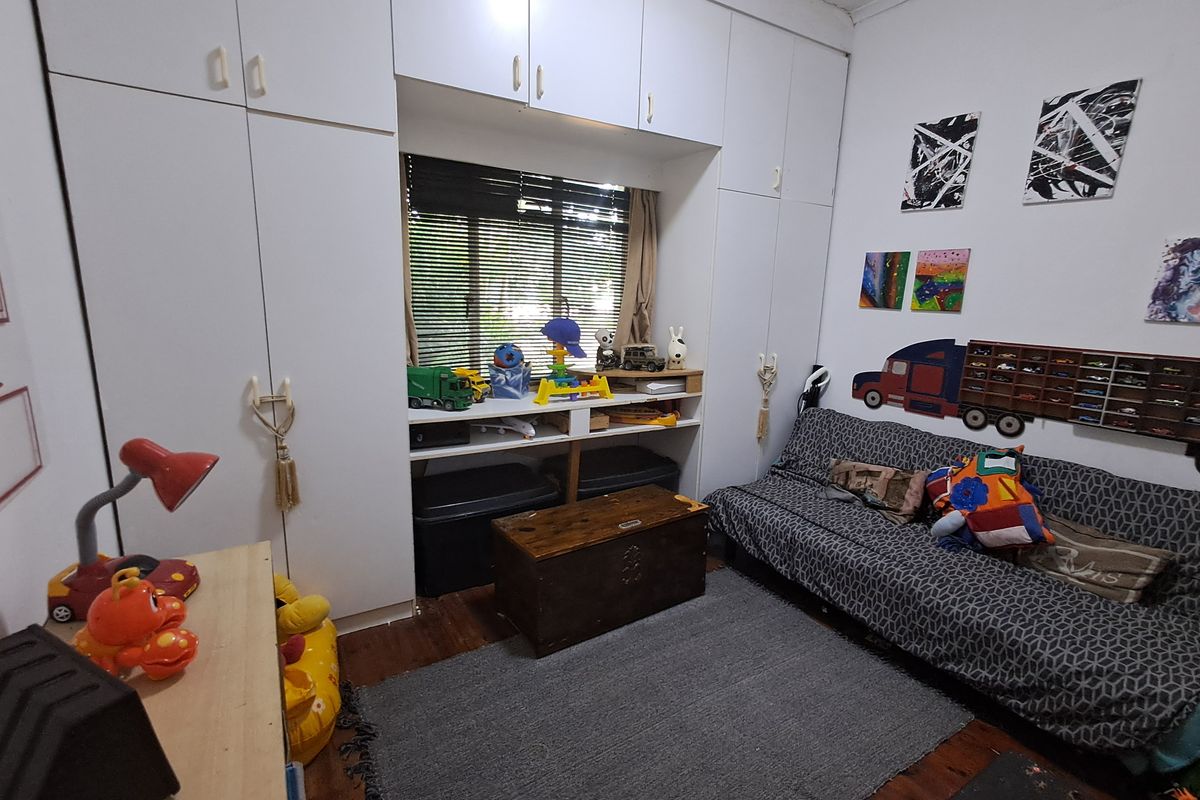 A bedroom featuring extensive built-in white cabinetry surrounding a central window, complemented by wooden flooring.