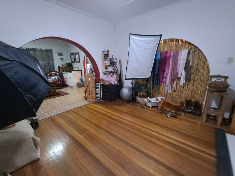 Living area featuring polished hardwood flooring and a distinctive arched doorway leading to an adjacent tiled room.
