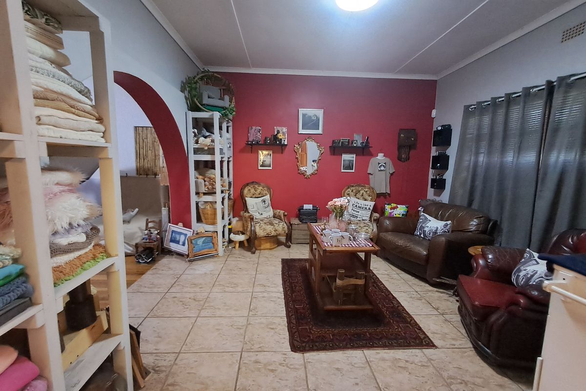 A living room featuring tiled flooring and an arched entryway leading to an adjacent space, with a prominent red accent wall.